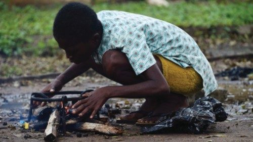 A boy works to light a fire for cooking in an internally displaced people's (IDP) camp, where flood ...