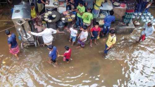 epa10264492 Bangladeshi people walk through a flooded area after the passing of Cyclone Sitrang, ...