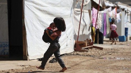 A Syrian refugee girl carries a child as she walks past tents at an informal camp, in the Bekaa ... A Syrian refugee girl carries a child as she walks past tents at an informal camp, in the Bekaa ...