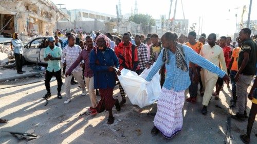 TOPSHOT - Residents carry the body of a victim in Mogadishu on October 30, 2022 after an car bombing ... TOPSHOT - Residents carry the body of a victim in Mogadishu on October 30, 2022 after an car bombing ...