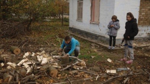 A boy saws wood for heating a house damaged during Russian military attacks in the village of ...