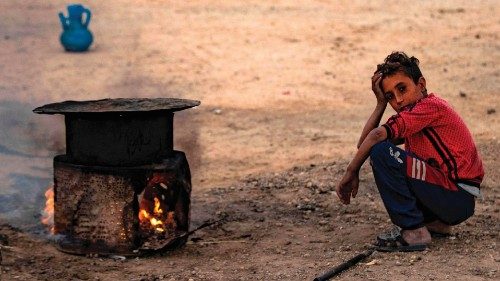 A Syrian boy squats by a makeshift stove at the Sahlah al-Banat camp for displaced people in the ...