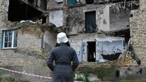 A woman looks at a graffiti made by Banksy on the wall of a heavily damaged building in the Gorenka ...