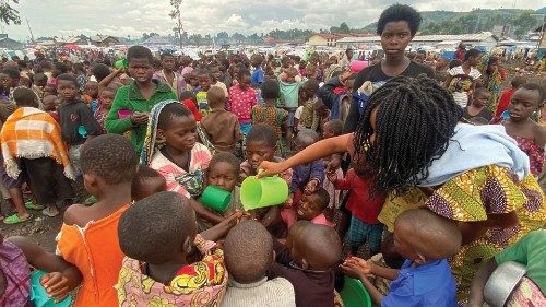 Internally displaced children wash their hands as they wait to receive porridge from volunteers at ...