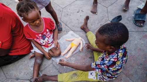 FILE PHOTO: Children play with a broken doll at the Hugo Chavez Square where they shelter from gang ...