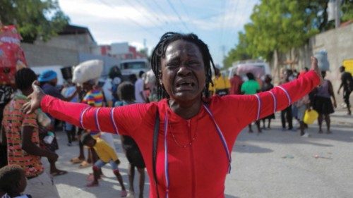 Rose Delpe cries as people displaced by gang war violence in Cite Soleil walk on the streets of ...