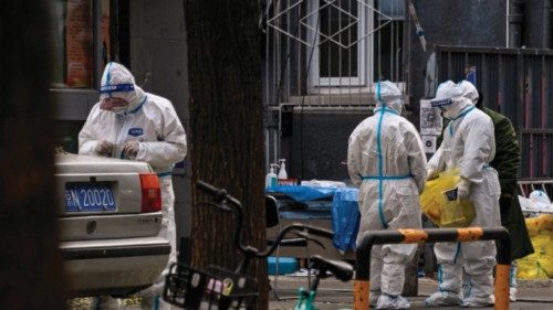 Workers wearing personal protective equipment (PPE) are seen by the entrance to a residential area ...