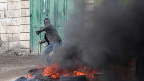 A Palestinian protester hurls rocks amid clashes with Israeli security forces in the village of Beit ...
