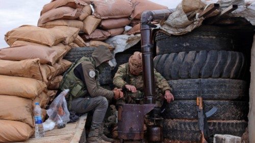 Fighters of the third corps of the Turkish-backed 'Syrian National Army' warm up by sandbags and ...