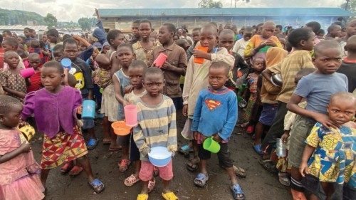 Internally displaced children wait to receive porridge from volunteers at Kayembe primary school in ...