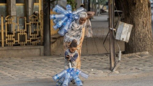TOPSHOT - A woman carrying plastic bottles helps her child in Dire Dawa, Ethiopia, on October 23, ...
