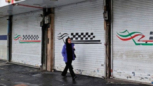 A woman walks past a closed shop along Satarkhan street in Iran's capital Tehran on December 5, ...