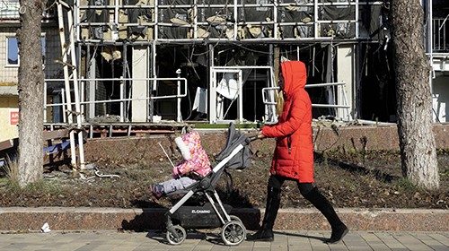 A mother and her child walk along a street in the Russian-occupied Azov Sea port city of Mariupol in ...