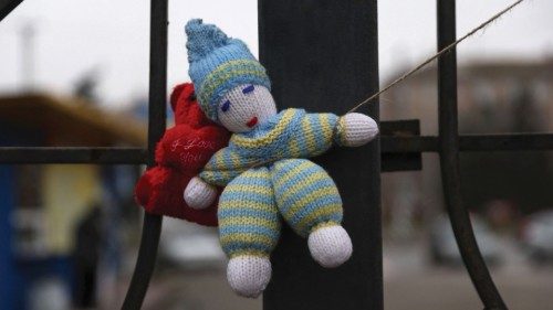 A stuffed toy hangs at the fence, marking a memorial for 60 civilians including seven children, who ...