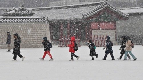 Visitors walk through Gyeongbokgung palace during snowfall in central Seoul on December 15, 2022. ...
