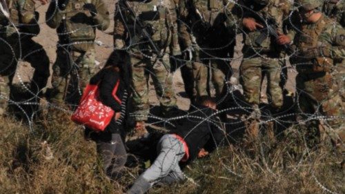 TOPSHOT - Migrants cross the razor fence placed by elements of the Texas National Guard on the banks ...