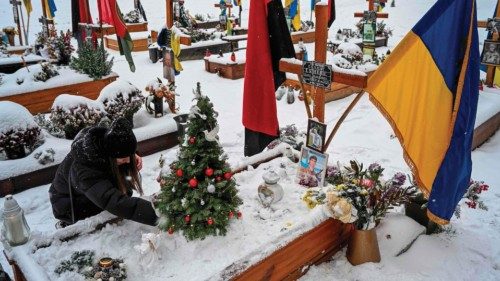 A woman decorates a Christmas tree at the grave of her husband Oleg Skybyk, a Ukrainian serviceman ...