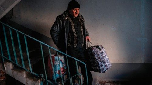 A local resident carries his belongings down the stairs after his apartment was damaged by Russian ...