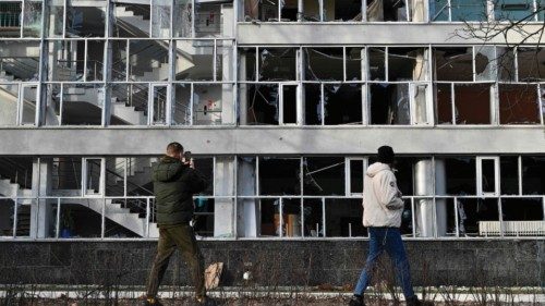 Bystanders look at an educational building in Kyiv on January 1, 2023, which was damaged by a ...