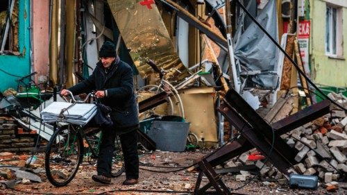 TOPSHOT - A local resident pushes his bicycle past 'hedgehog' tank traps and rubble, down a street ...