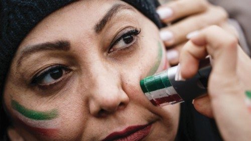 epa10396035 A protester gets her face colored with Iranian flag during a rally to commemorate the ...