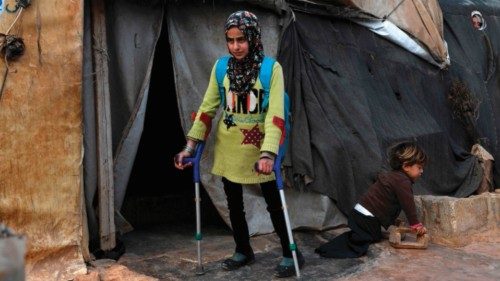 Syrian Maya Merhi, with the support of crutches, walks next to her disabled brother outside the ...