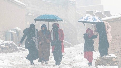 Afghan women hold umbrellas as they walk down a street during snowfall in Kabul on January 8, 2023. ...