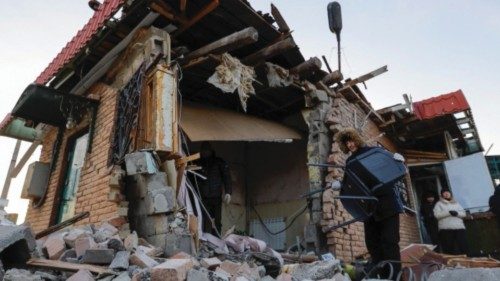 Local residents remove debris and carry belongings out of a shop destroyed in recent shelling in the ...