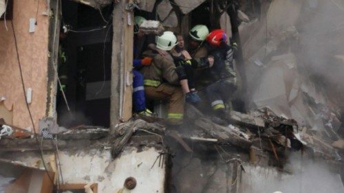 Emergency personnel evacuate a woman at the site where an apartment block was heavily damaged by a ...