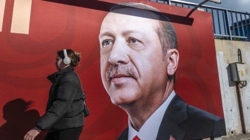 epa10413230 A woman walks in front of a picture of the Turkish President Recep Tayyip Erdogan in ...