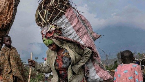 TOPSHOT - Internally displaced people (IDP) carry charcoal from the forest at the foot of Nyiragongo ...