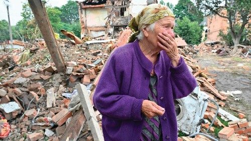 TOPSHOT - A local resident, Raisa Kuval, 82, reacts next to a damaged building partially destroyed ...