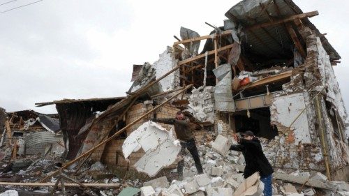 Local residents remove debris from a house of their  neighbour damaged by a Russian military strike, ...