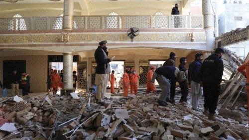 Locals and rescue workers stand amid the rubble, after a suicide blast in a mosque in Peshawar, ...