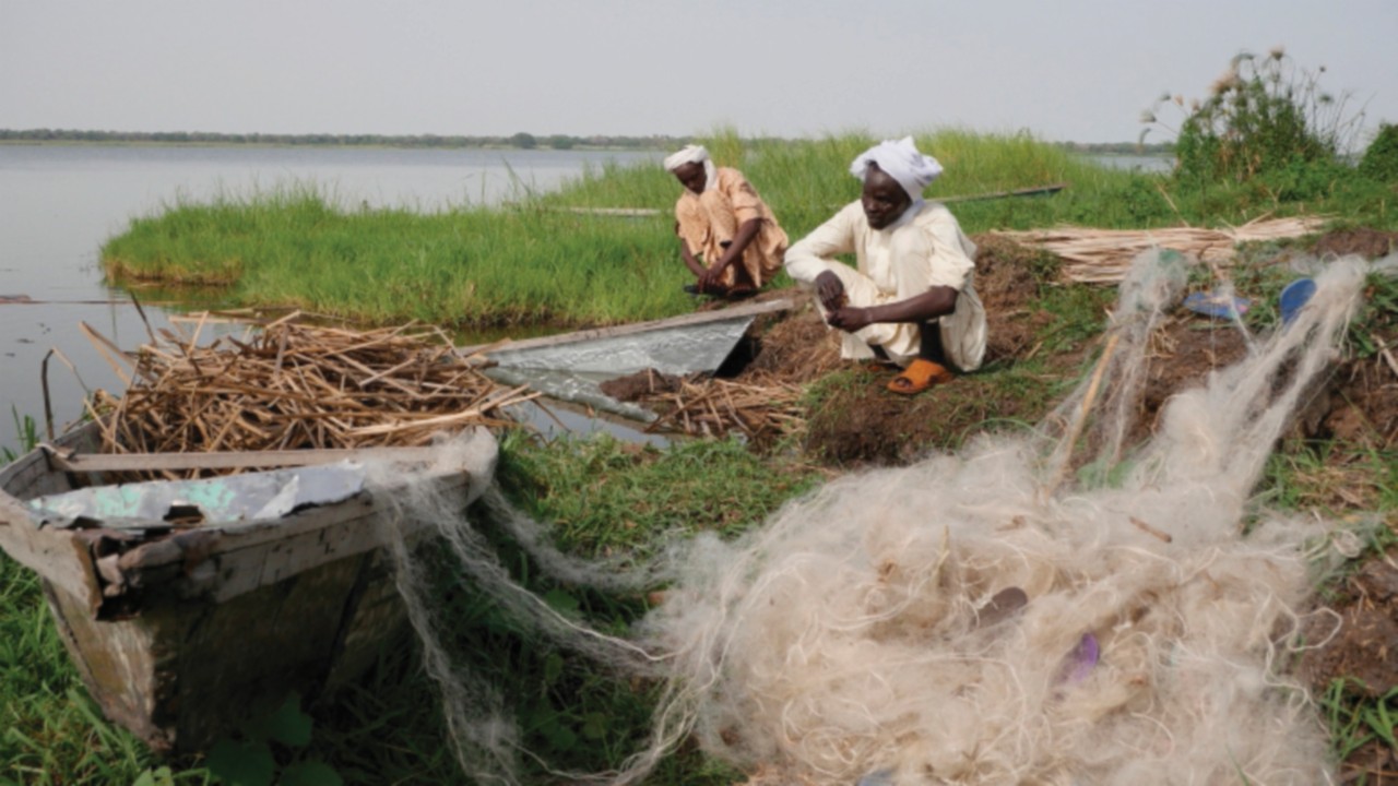 Chadian fishermen mend their nets on Midikouta Island on Lake Chad on July 22, 2017. - Tchoukouli -- ...