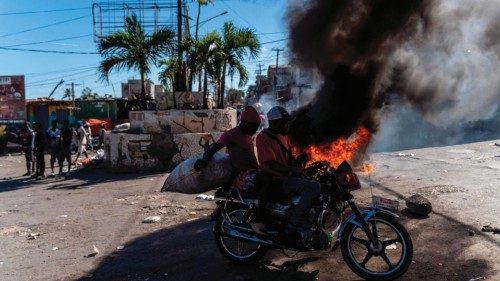 TOPSHOT - Men on a motorcycle drive past by burning tires during a demonstration after a gang attack ...