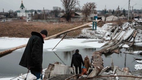 People walk on a destroyed bridge to cross a canal towards the disputed area in Bakhmut on February ...