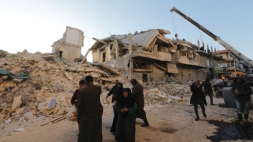 People walk past damaged buildings, in the aftermath of an earthquake, in rebel-held town of ...