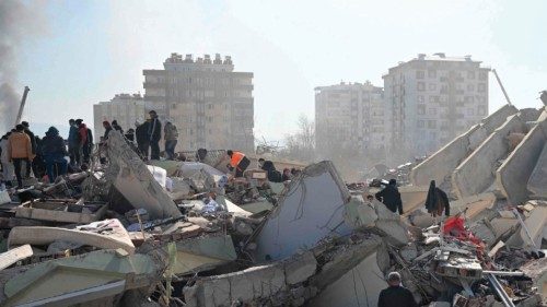 Families of victims stand as rescue officials search among the rubble of collapsed buildings in ...