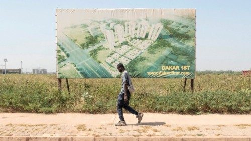 A construction worker walks past advertising for a new city in Diamniadio on November 16, 2022. - ...