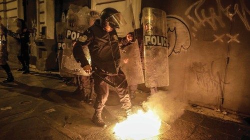 epa10458223 A policeman tries to put out a fire on a shield of the security forces, during an ...