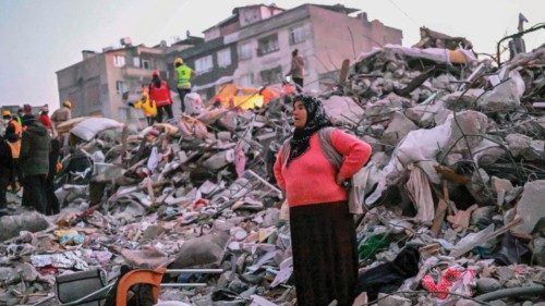 TOPSHOT - A woman stands in the rubble hoping her relatives to be found by rescuers in Hatay on ...