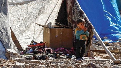 A displaced Syrian child stands outside a tent at a temporary accommodation centre erected to ...