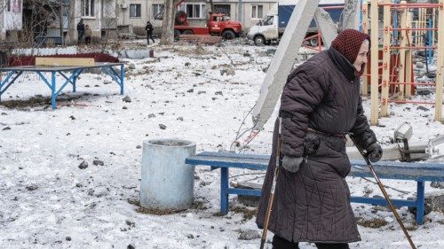 A woman walks on a playground after an apartment block was heavily damaged by a missile strike, amid ...