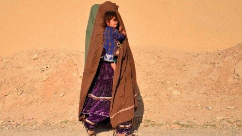 TOPSHOT - A woman carrying a child walks along a roadside in Zhari district of Kandahar province on ...
