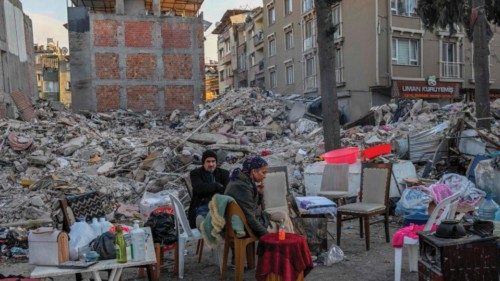 TOPSHOT - Displaced quake-hit residents sit with their belongings near the collapsed buildings in ...