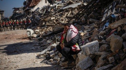 epa10470083 A man sits on the debris of collapsed buildings after a powerful earthquake, in Hatay, ...