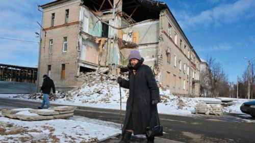 An elderly local resident walks past a building destroyed as a result of shelling in the Ukrainian ...