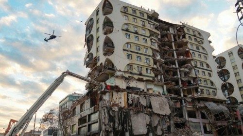 TOPSHOT - This photograph taken on February 22, 2023, shows a crane demolishing a damaged building ...