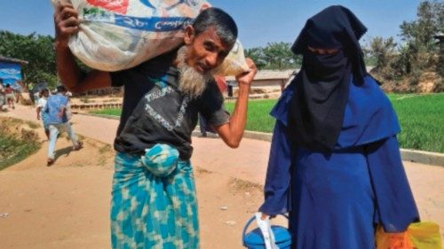 Rohingya refugees carry relief material after collecting from a distribution point in Kutupalong ...